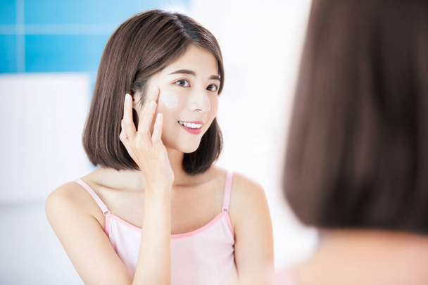 woman apply cream on face - Фото, изображение