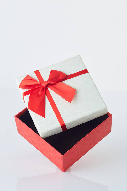 Белая подарочная коробка с красным бантом на белом
 - Фото, изображение