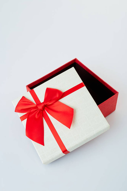 Valkoinen lahjapakkaus, jossa punainen nauha rusetti valkoisella
 - Valokuva, kuva