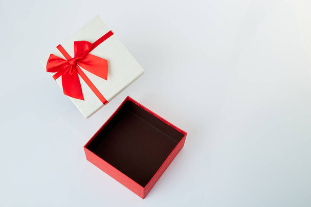Біла подарункова коробка з червоною стрічкою на білому
 - Фото, зображення