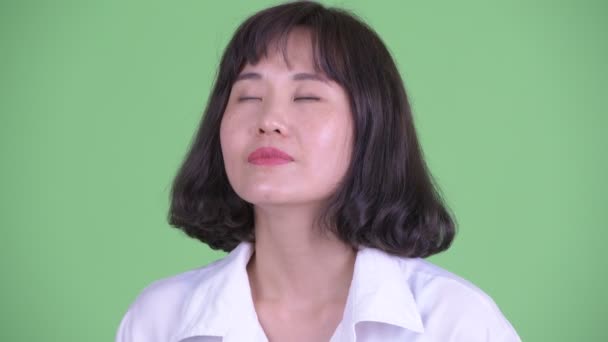 Rostro de feliz hermosa mujer de negocios asiática relajante con los ojos cerrados
 - Metraje, vídeo