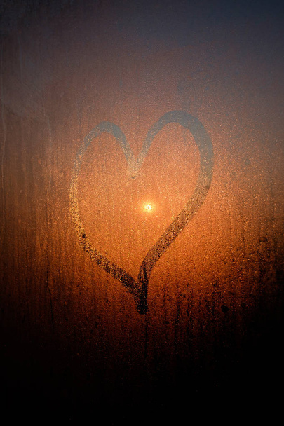 Drawed heart on condensated window with sunrise on background - Photo, Image
