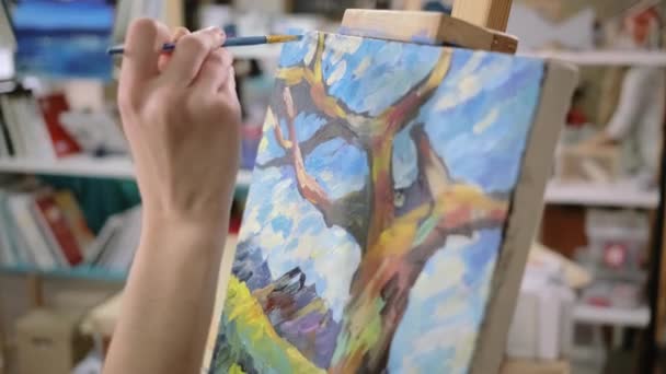 Καλλιτέχνης εφαρμόζει πινελιές φινίρισμα σε εικόνες τοπίου, γκρο πλαν του καμβά - Πλάνα, βίντεο
