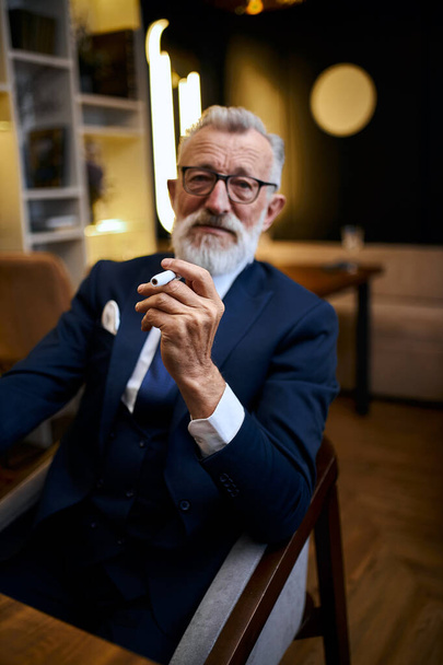 Handsome senior man in suit smoke e-cigarette in restaurant - Fotografie, Obrázek