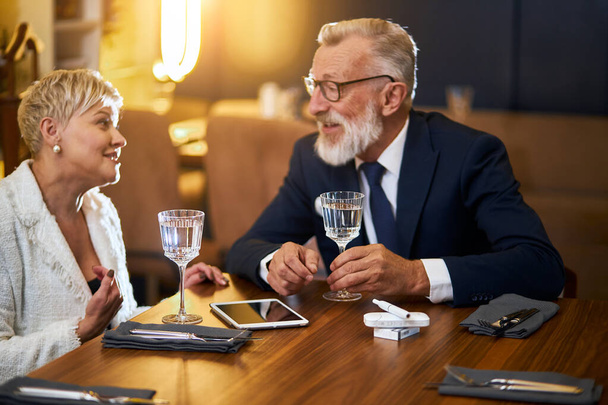 Attractive senior couple sitting in restaurant table and speaking - 写真・画像