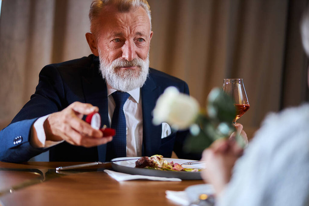 Mature elegant man proposing to a woman with rose - Foto, afbeelding