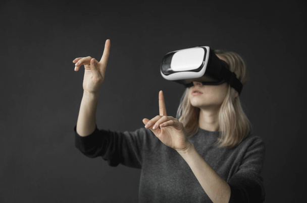 Young woman wearing virtual reality goggles headset, vr box. Connection, technology, new generation, progress concept. Girl trying to touch objects in virtual reality. - Foto, imagen