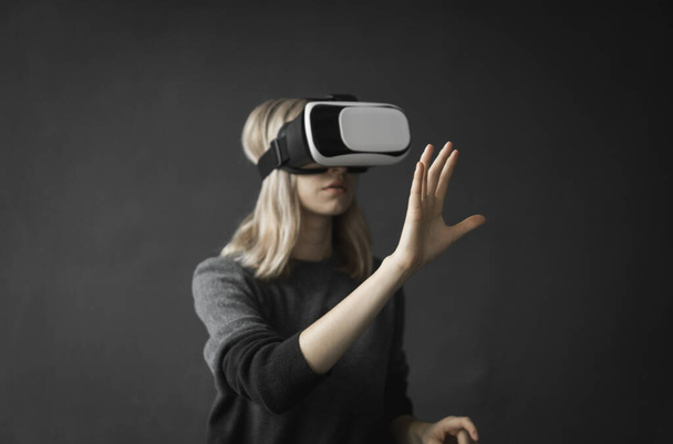 Young woman wearing virtual reality goggles headset, vr box. Connection, technology, new generation, progress concept. Girl trying to touch objects in virtual reality. - Valokuva, kuva