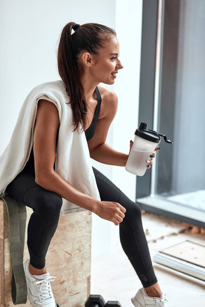 Fit woman holding plastic bottle of water after workout - Zdjęcie, obraz