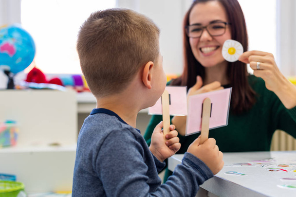 Children speech therapy concept. Preschooler practicing correct pronunciation with a female speech therapist. - Photo, image