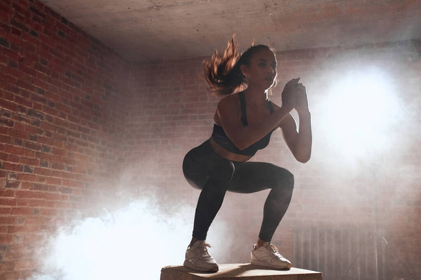 Donna in forma sportiva che salta accovacciati sulla scatola in forma
 - Foto, immagini