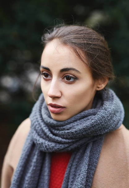 Close up autumn outdoor portrait of beautiful young woman in autumn park in knitted scarf. - 写真・画像