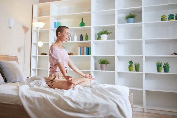 Quiet woman practicing yoga exercise on bed at home - Photo, image