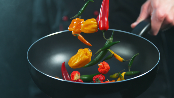 Super slow motion of chef holding frying with falling chilli peppers. Filmed on high speed cinema camera, 1000fps. - Footage, Video
