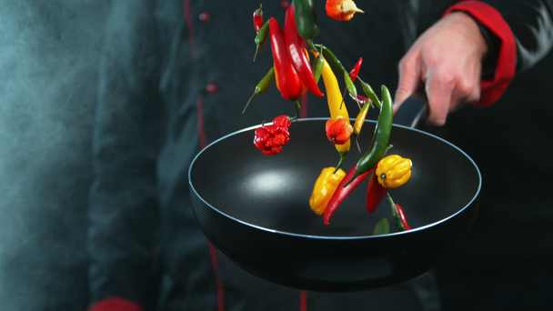 Super powolny ruch kucharza trzymającego smażenie z spadającą papryką chili. Nagrywane na szybkim aparacie kinowym, 1000fps. - Materiał filmowy, wideo