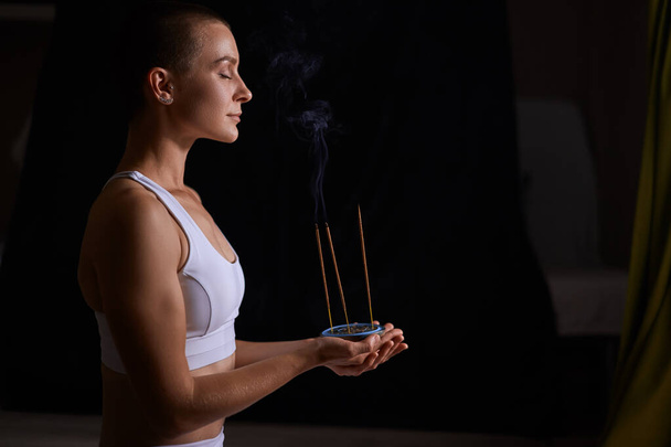 Fit woman relaxing with smoking aromatic sticks. aromatherapy, meditation - Photo, Image