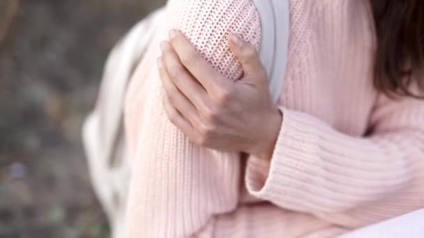 primo piano di bella ragazza in maglia maglione rosa con piccolo zaino seduto sulla coperta nella foresta autunnale e sorridente. - Filmati, video