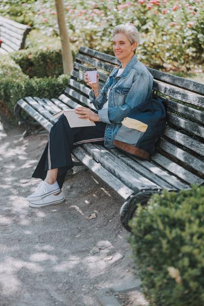 Female with a book sitting on the bench - Zdjęcie, obraz