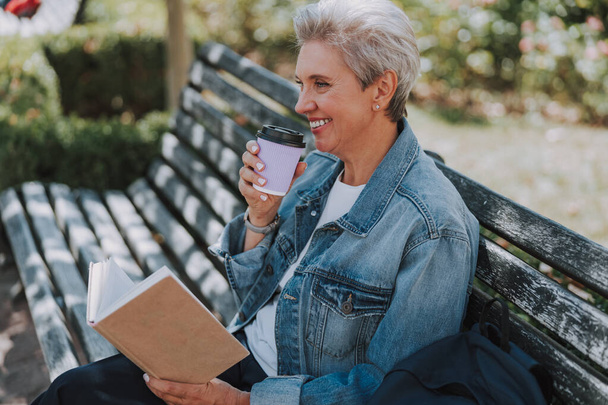 Cheerful woman drinking coffee on the bench - Foto, Bild