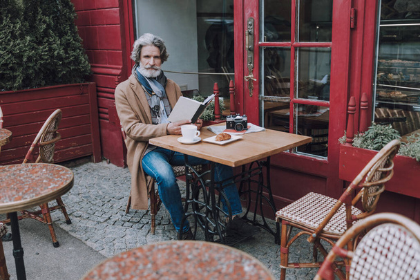 Serious bearded man with book in cafe stock photo - Foto, Bild