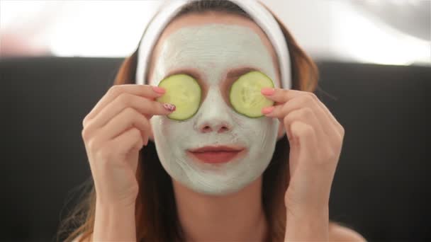Close Up of a Girl With a Mask On Her Face And a Towel On Her Head That Closes Her Eyes With Cucumbers And Smiles. Woman Wearing Face Mask. Face Care Concept - Footage, Video
