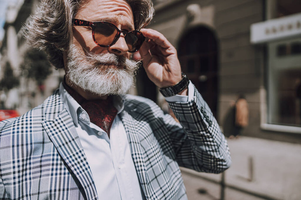 Bearded mature man touching sunglasses stock photo - Photo, image