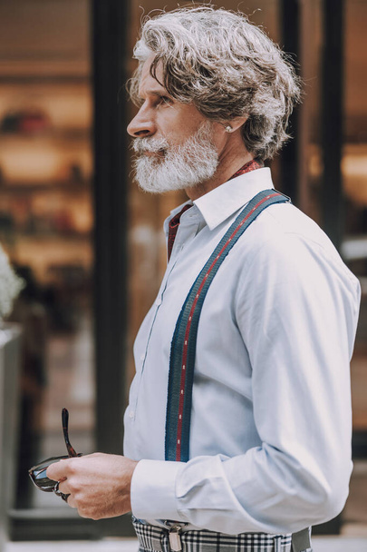Stylish man standing outdoors in shirt with suspenders stock photo - Photo, image