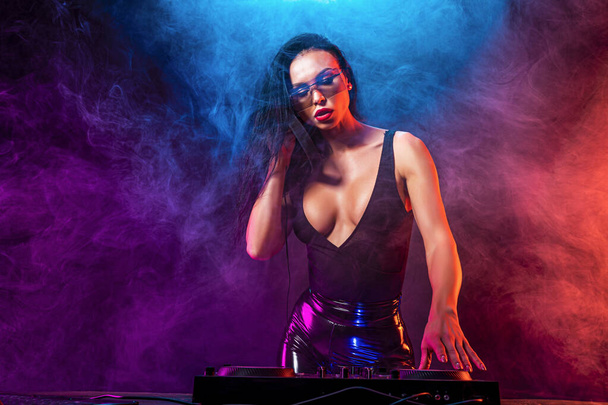 Young sexy woman dj playing music. Headphones and dj mixer on table. - 写真・画像