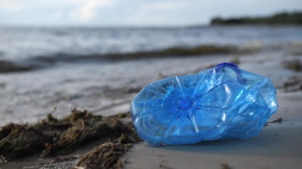 Una botella de plástico se encuentra en la orilla del mar. Las olas golpearon la orilla. Playa contaminada. 4K Slow Mo
 - Imágenes, Vídeo