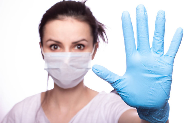 junge Frau mit medizinischer Maske im Gesicht, Handschuhe an den Händen - Foto, Bild