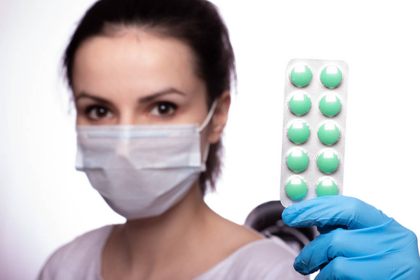mujer joven en una amapola médica y guantes con pastillas
 - Foto, imagen