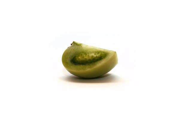 Кусок маринованного зелёного томата на белом фоне
 - Фото, изображение