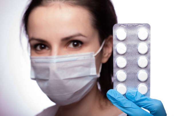 молодая женщина в медицинском маке и перчатках с таблетками
 - Фото, изображение