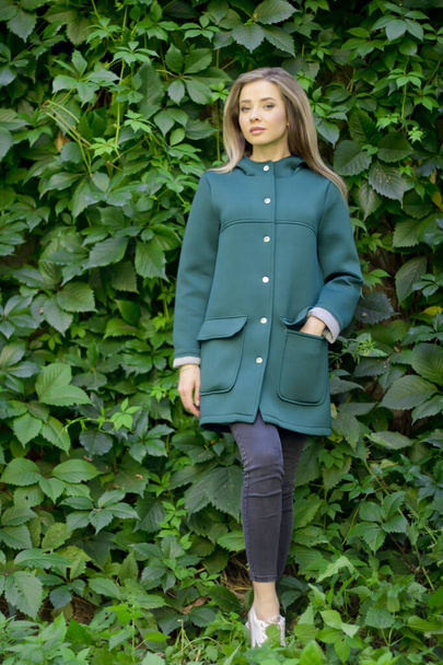 Портрет красивої дівчини в зеленому пальто на фоні плюща
 . - Фото, зображення