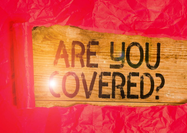 Conceptual hand writing showing Are You Covered Question. Business photo showcasing asking showing if they had insurance in work or life Cardboard which is torn placed above a wooden classic table. - 写真・画像