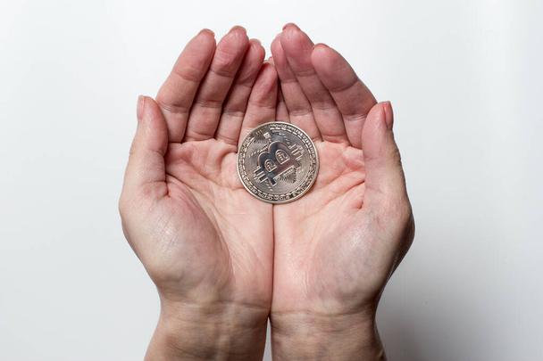 Bitcoin coin in the hands of a girl on a white background - Φωτογραφία, εικόνα