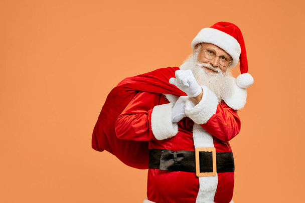 Happy Santa Claus carrying on big red bag full of presents - Photo, Image