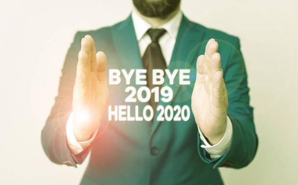 Word writing text Bye Bye 2019 Hello 2020. Üzleti koncepció a tavalyi évtől való elbúcsúzásra és egy másik jó üdvözlésére Man with opened hands in fron the table. Mobiltelefon és jegyzetek a fül - Fotó, kép