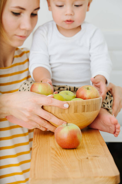 lly blond toddler boy is explores, plays with apples from backet. - 写真・画像