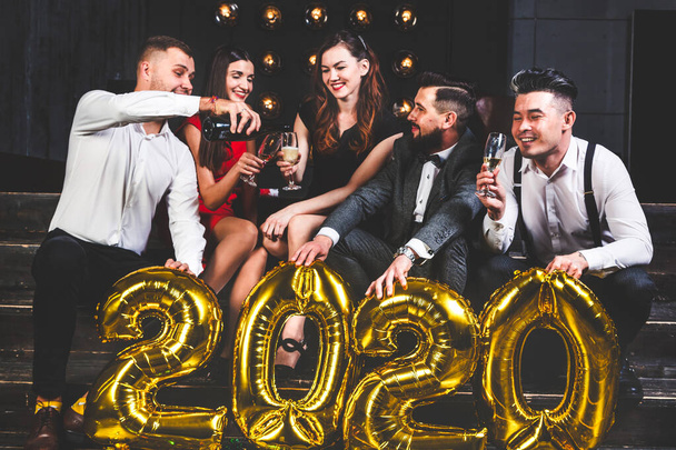 Gyönyörű fiatalok egy vállalati bulin, akik léggömböket tartanak 2020-ban. Boldog újévi ünnepséget! Club party a barátokkal - Fotó, kép