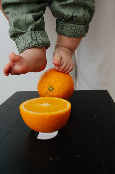 Baby feet touched orange. Close up image - Fotografie, Obrázek