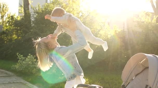 Mutter und Tochter vergnügen sich im Sommerpark bei einem Spaziergang. Glückliche Mutter wirft kleine Tochter hoch - Filmmaterial, Video
