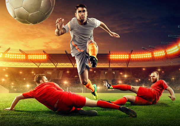 スタジアムでサッカーの試合。選手はボールのために戦う。ファンが応援する劇的な夜空  - 写真・画像