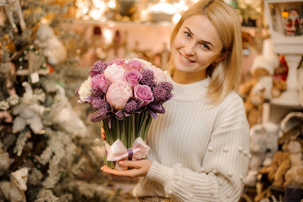 Smiling girl holding a bouquet of tender pink and purple color flowers with green stalks - Фото, изображение