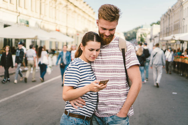 Couple tourists consulting city and mobile phone gps in street. People traveling. Couple checking location in smart phone. Technology in lifestyle. girl using navigator system app on smart phone - Photo, Image