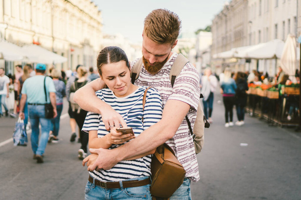 Couple tourists consulting city and mobile phone gps in street. People traveling. Couple checking location in smart phone. Technology in lifestyle. girl using navigator system app on smart phone - Фото, зображення