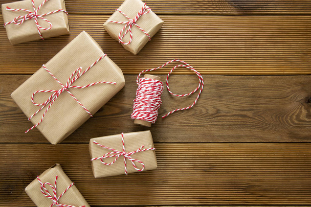 Kerst achtergrond. Geschenken dozen verpakt in ambachtelijk papier over houten achtergrond. Top uitzicht, rustieke stijl. Kopieerruimte. - Foto, afbeelding