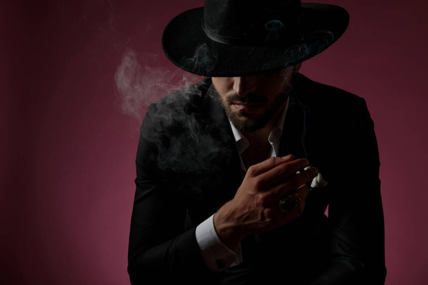Motivovaný záhadný muž kouřící a ukazující svůj prsten - Fotografie, Obrázek