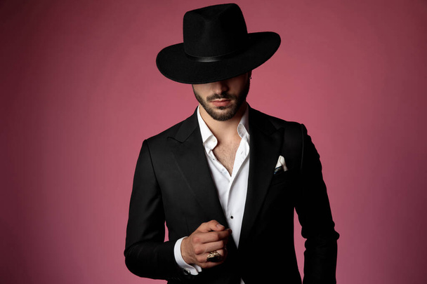 Hombre serio vistiendo un traje negro y sombrero
 - Foto, Imagen