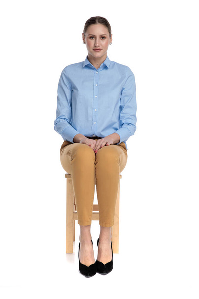 nuori liikenainen yllään sininen paita ja istuu
 - Valokuva, kuva
